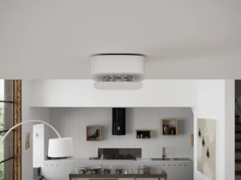 Détecteur de fumée au plafond d'une maison avec une cuisine en arrière-plan