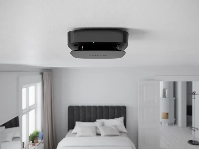 Détecteur de fumée au plafond d'une maison avec une cuisine en arrière-plan
