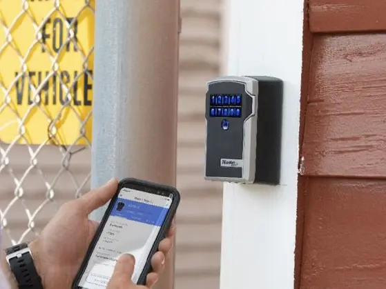 Smartphone qui ouvre une boîte à clé fixée sur un mur extérieur